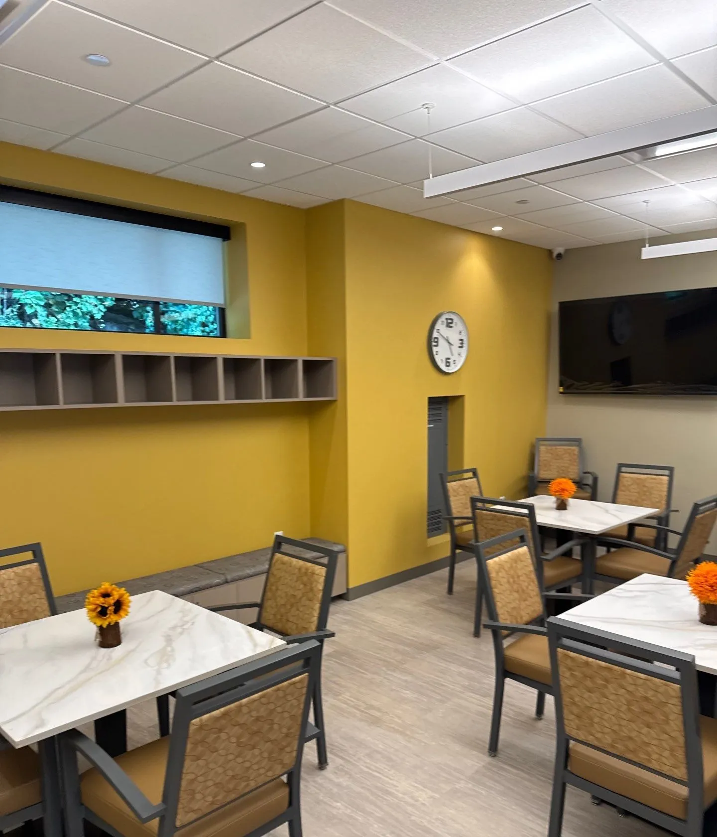 Finished dining area with yellow accent wall, cubbies, and tables in a Kansas City tenant finish