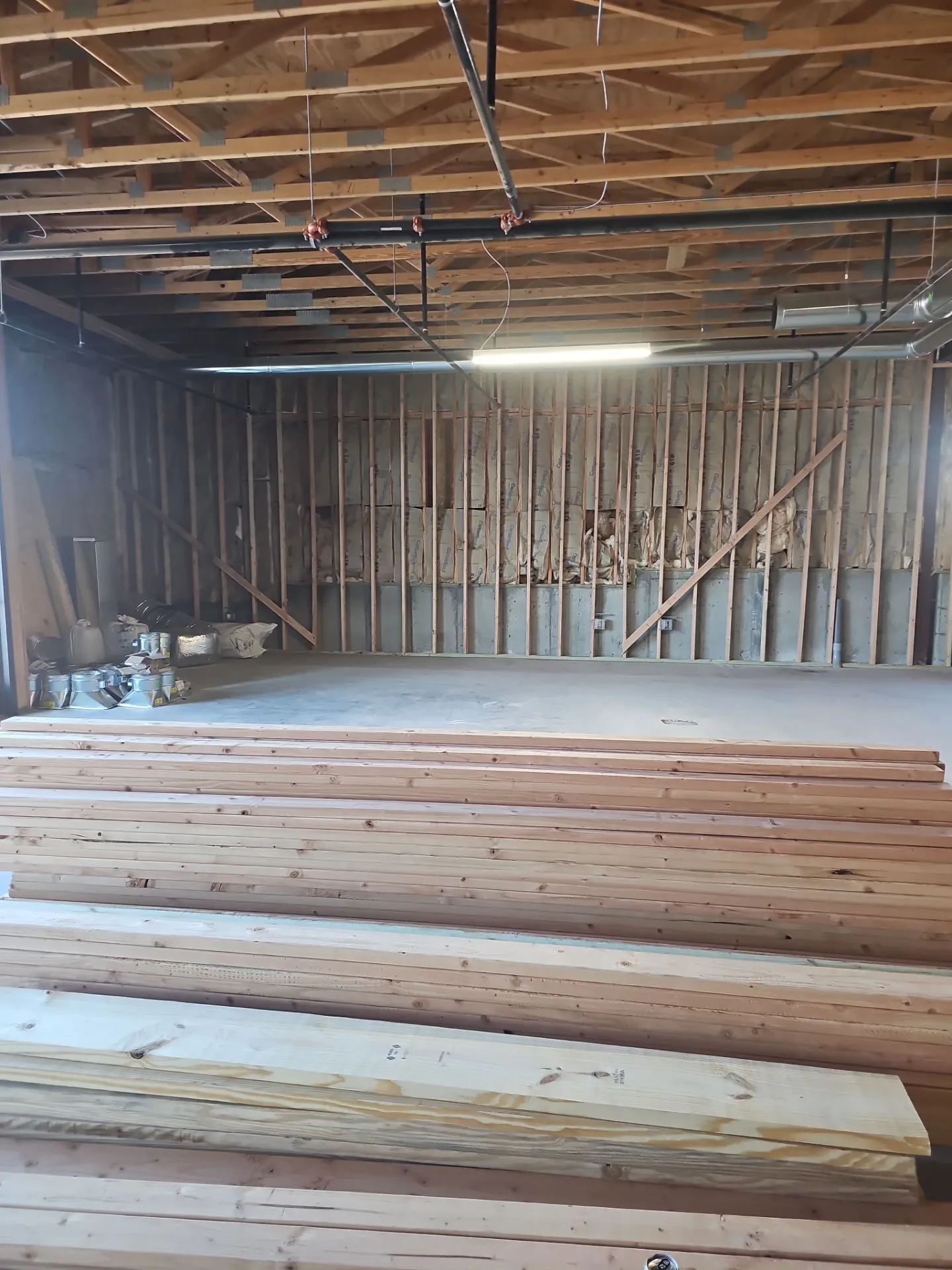 Exposed wall framing and stacked lumber during a Kansas City tenant-finish project